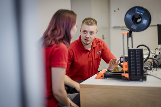 Mann erklärt Frau einen 3D Drucker